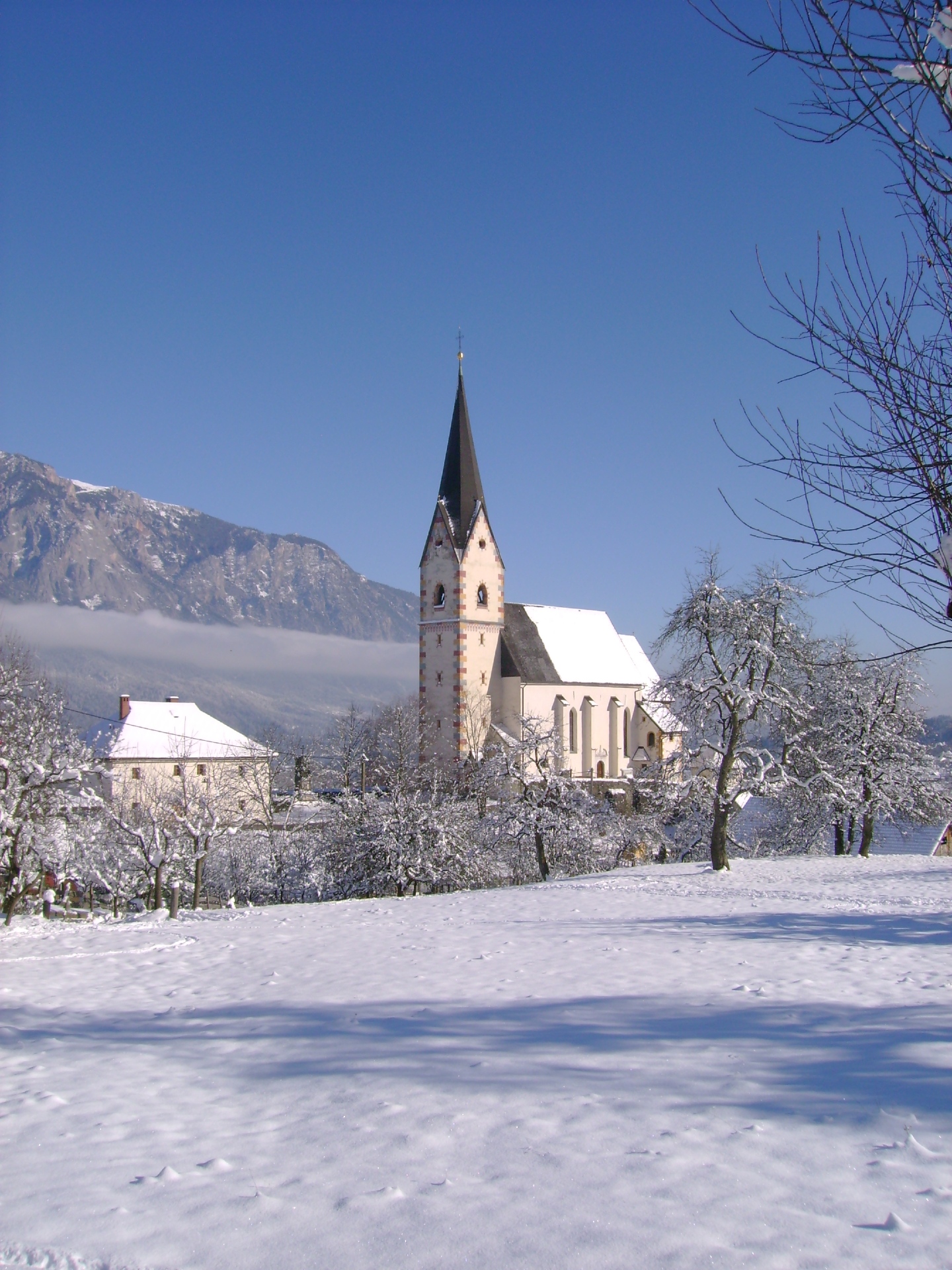 Blick auf die verschneite Filialkirche Mariae Name in der Ortschaft Göriach